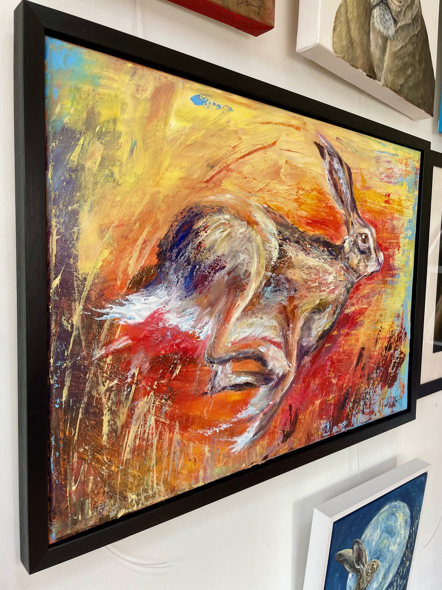 Side view of painting of a hare in a black frame by Debbie Storey