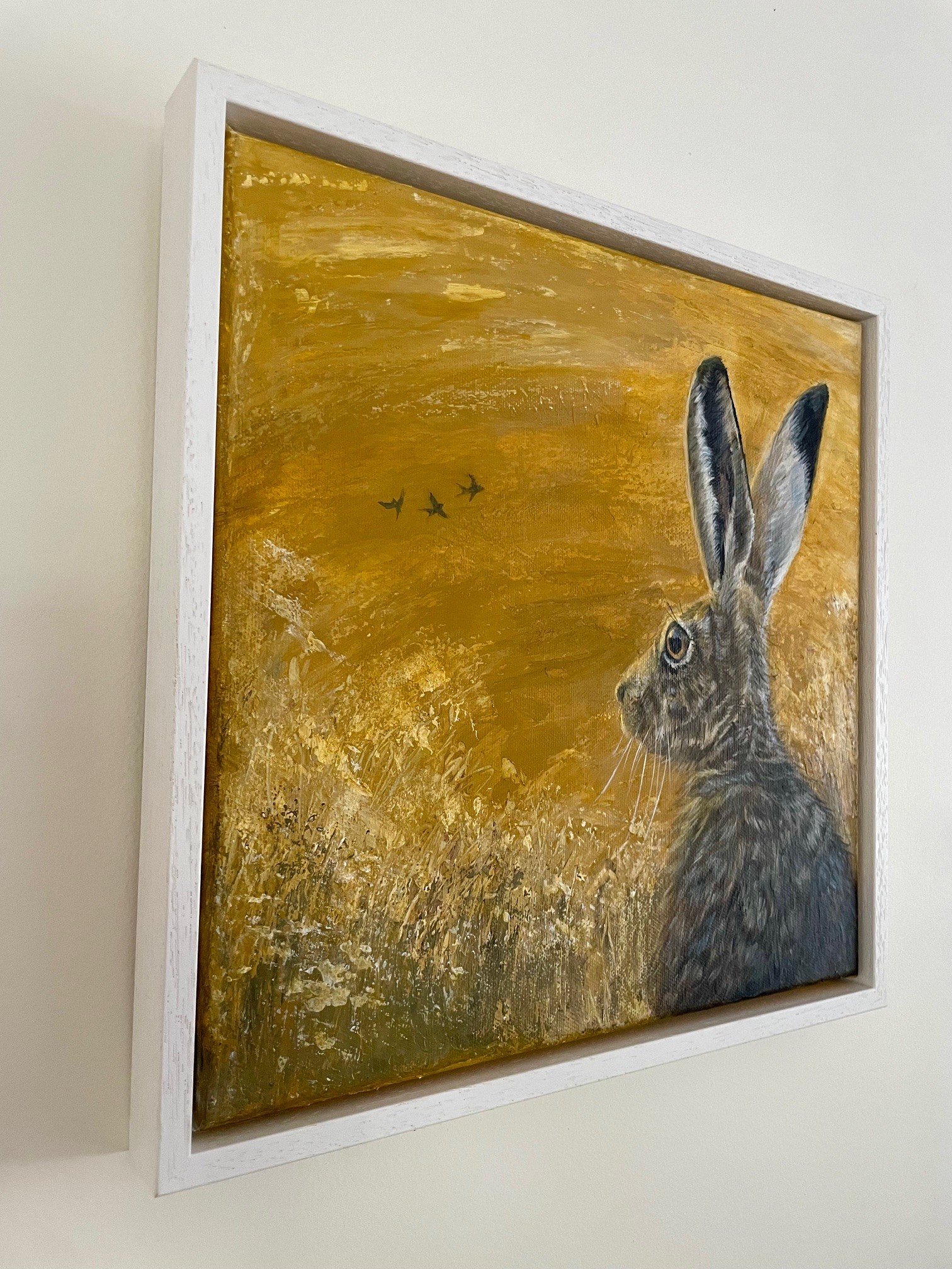 Painting of a hare with a yellow background in a white frame by Debbie Storey