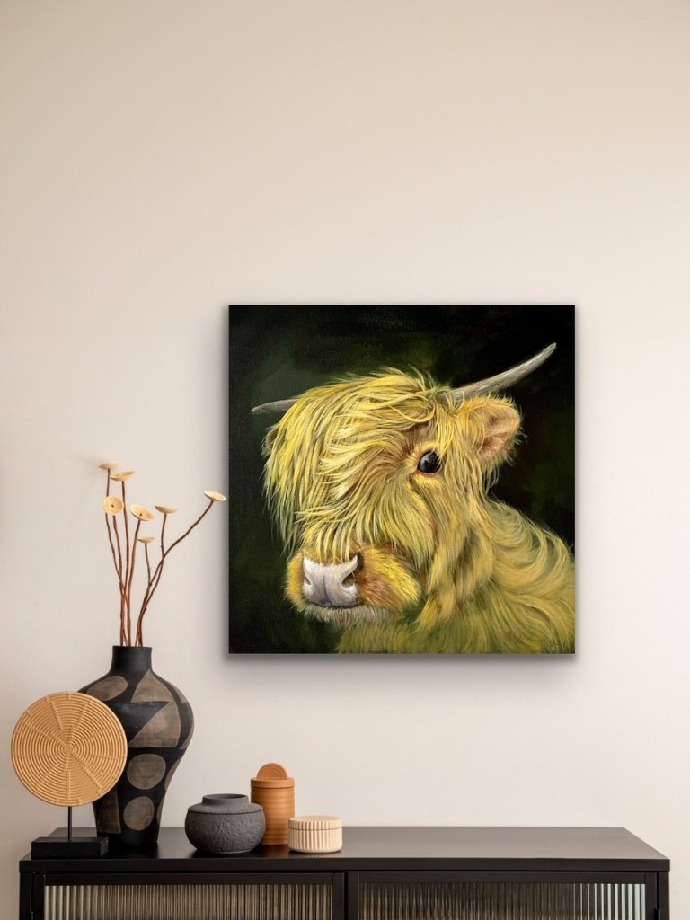 Acrylic painting of a highland cow on a black background hanging on a wall above a shelf