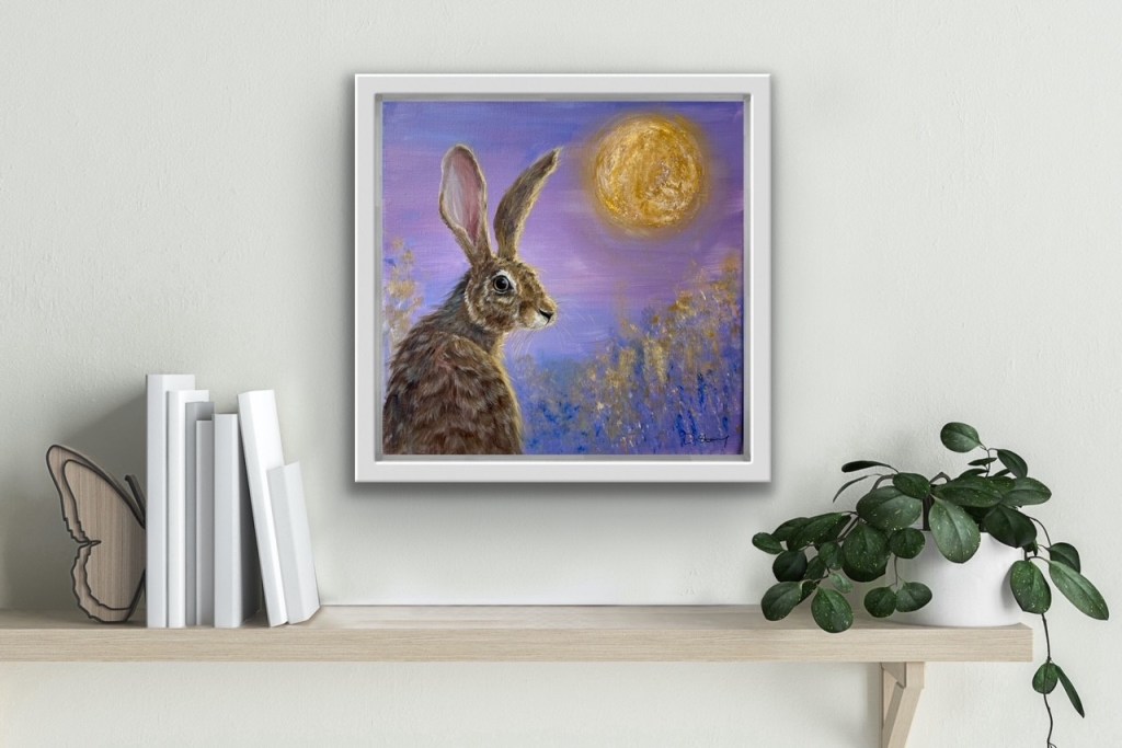 Painting of a purple hare  with a gold moon in the background hanging on a white wall