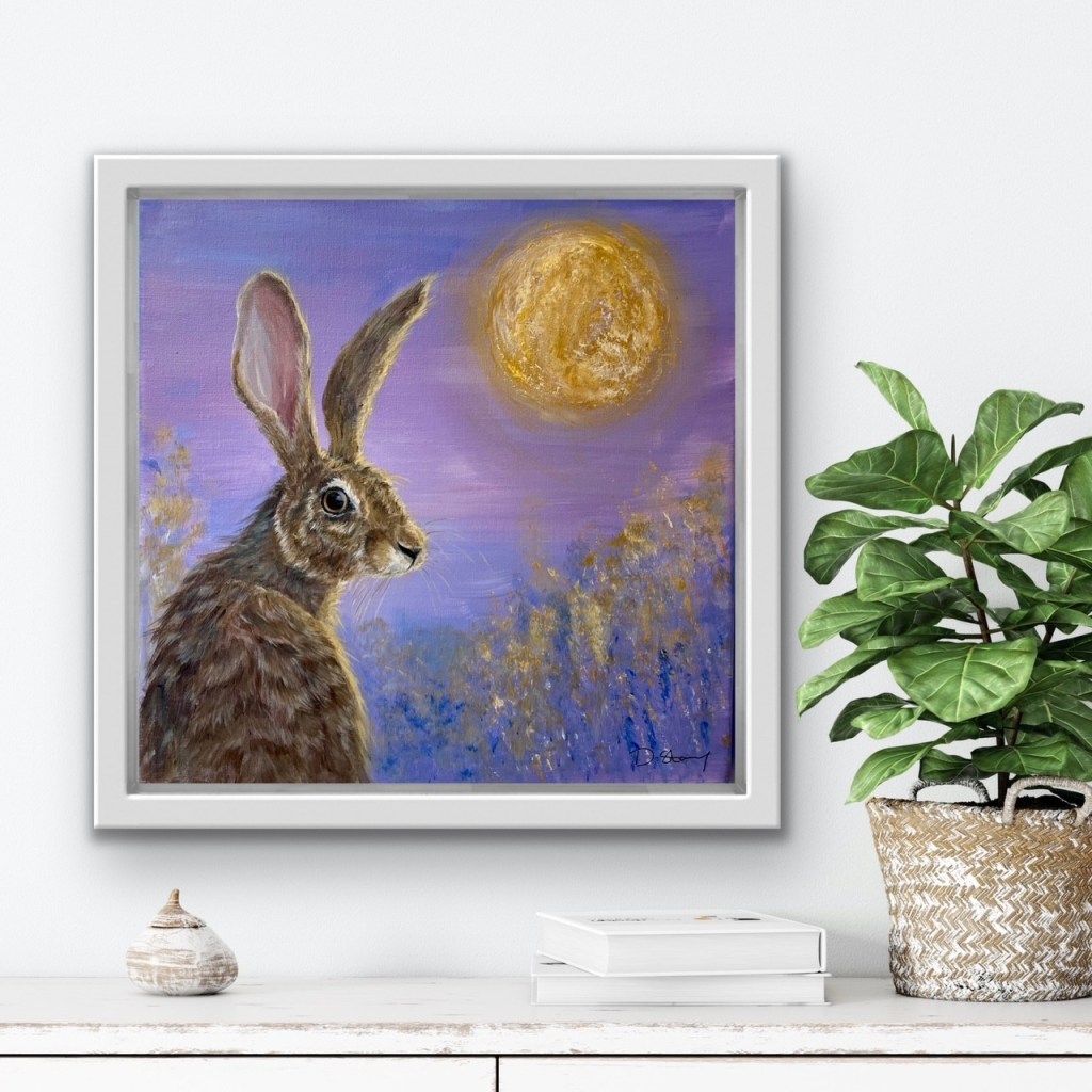 Painting of a purple hare  with a gold moon in the background hanging on a white wall
