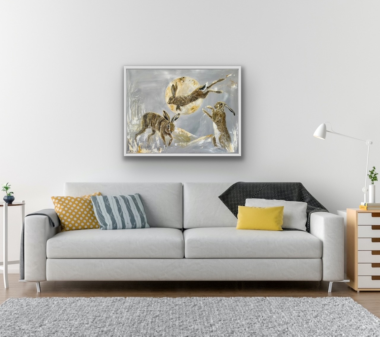 Painting of three hares by Debbie Storey on a white wall with a settee in the foreground